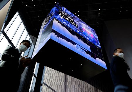 Men wearing protective face masks walk under an electronic board showing Japan's Nikkei share average inside a conference hall, amid the coronavirus disease (COVID-19) pandemic, in Tokyo, Japan January 25, 2022. REUTERS/Issei Kato Men wearing protective face masks walk under an electronic board showing Japan's Nikkei share average inside a conference hall, amid the coronavirus disease (COVID-19) pandemic, in Tokyo, Japan January 25, 2022. REUTERS/Issei Kato