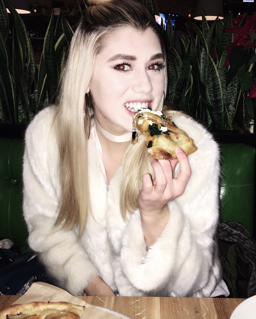 A guide to healthy restaurants in Chicago. Photo of woman eating Vegan pizza.