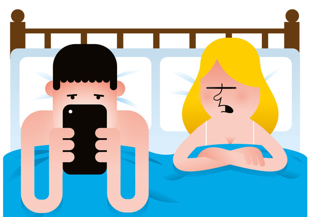 A man and woman in bed while the man is looking at a mobile device