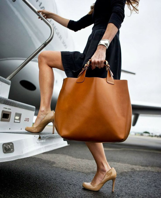 Девушка в черной юбке, джемпере и с коричневой сумкой тоут