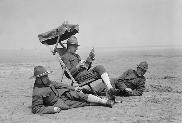 Американский солдат читает газету, сидя в раскладном кресле, 1918 год