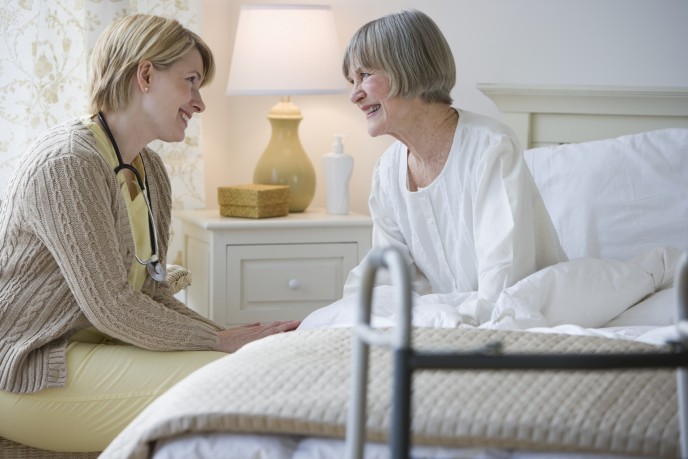 Nurse talking to senior woman in bed