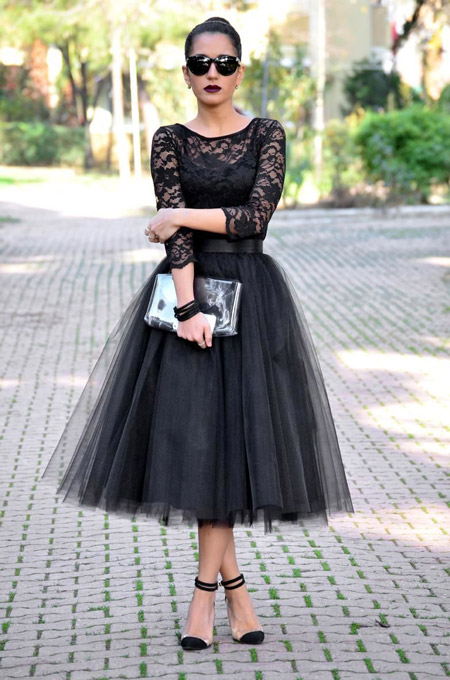 Модель в черной фатиновой юбке миди и кружевной блузе