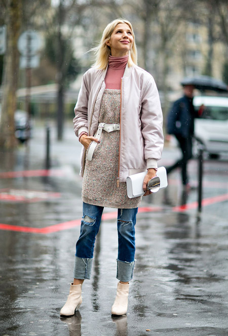 Девушка в рваных джинсах, розовая водолазка, туника и куртка, светлые ботильоны и клатч