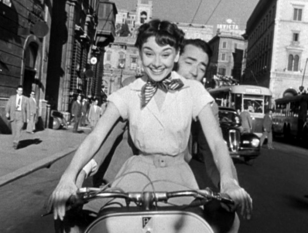 Audrey_Hepburn_and_Gregory_Peck_on_Vespa_in_Roman_Holiday_trailer