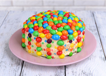 Delicious rainbow cake on plate on table close-up