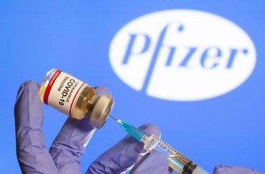 A woman holds a small bottle labeled with a "Coronavirus COVID-19 Vaccine" sticker and a medical syringe in front of displayed Pfizer logo in this illustration taken, October 30, 2020. REUTERS/Dado Ruvic A woman holds a small bottle labeled with a "Coronavirus COVID-19 Vaccine" sticker and a medical syringe in front of displayed Pfizer logo in this illustration taken, October 30, 2020. REUTERS/Dado Ruvic