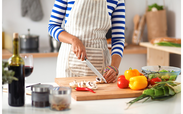 Young woman cutting vegetables in kitchen, isolated