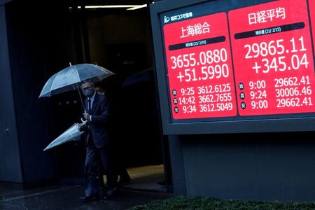 Men holding umbrellas walk near an electric board showing Nikkei index a brokerage in Tokyo, Japan February 15, 2021. REUTERS/Kim Kyung-Hoon Men holding umbrellas walk near an electric board showing Nikkei index a brokerage in Tokyo, Japan February 15, 2021. REUTERS/Kim Kyung-Hoon