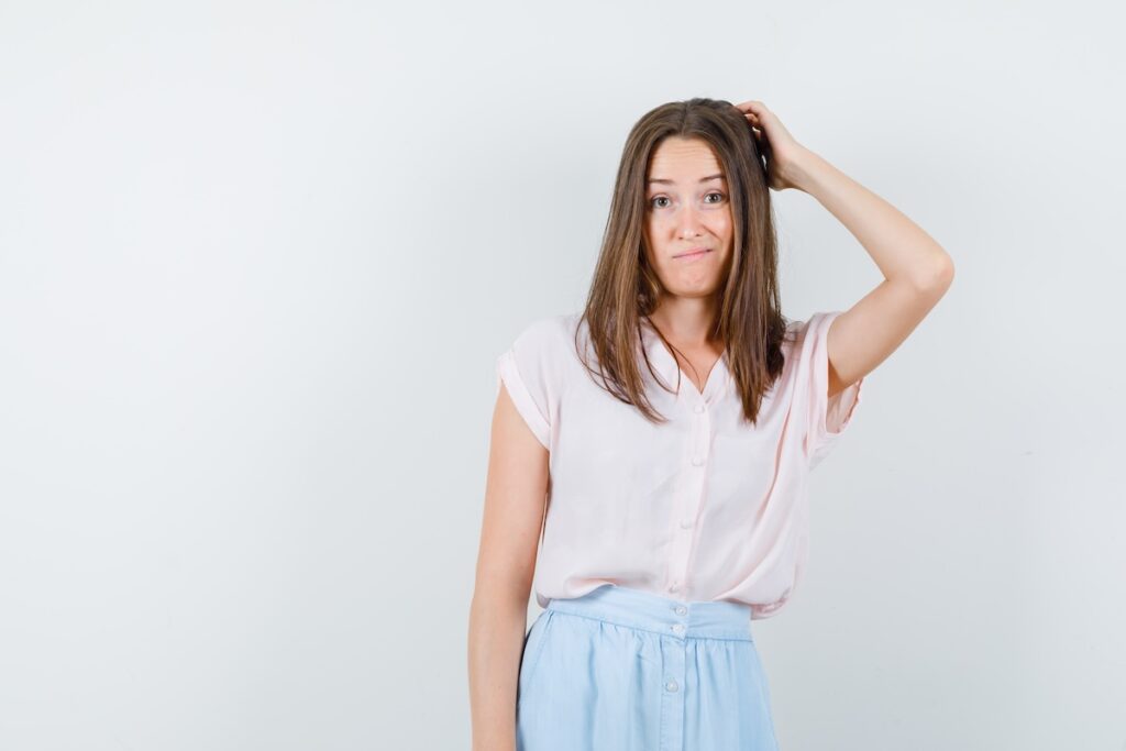 young woman scratching head while thinking t shirt skirt looking hesitant front view