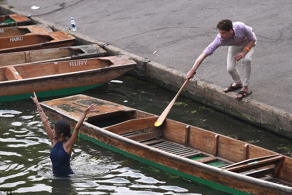 A passerby attempts to coax one female student back to shore after she jumped into the River Cam this morning