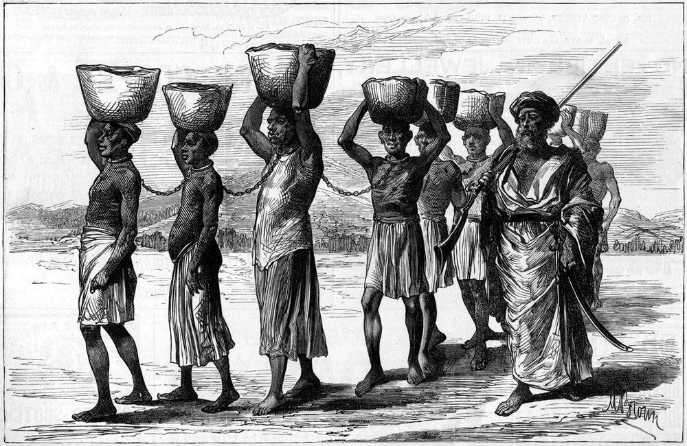 Колонна скованных между собой африканских рабов с грузом на головах под охраной пеших работорговцев (Восточная Африка, 1880-е годы)