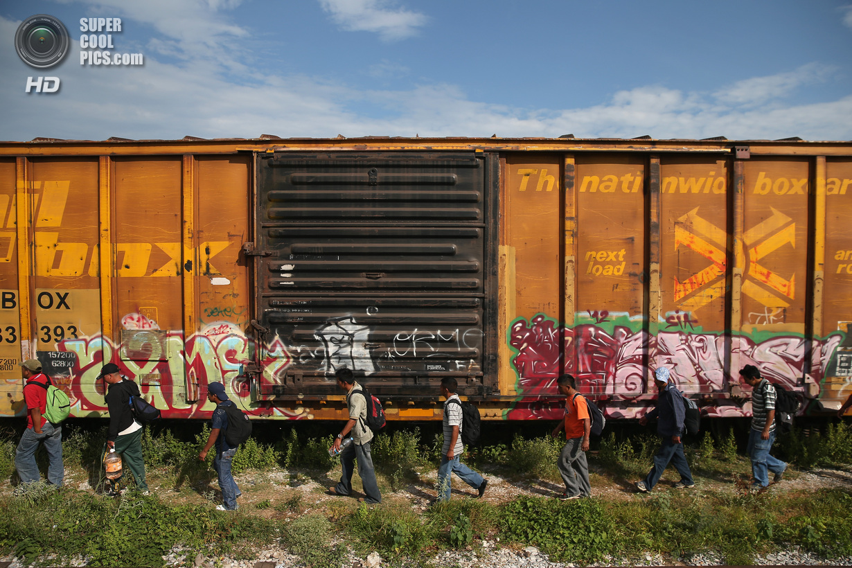 Мексика. Сьюдад-Истепек, Оахака. 4 августа. Гватемальские нелегальные иммигранты слазят с грузового поезда после 15-часовой поездки на его крыше, чтобы перекусить. (John Moore/Getty Images)