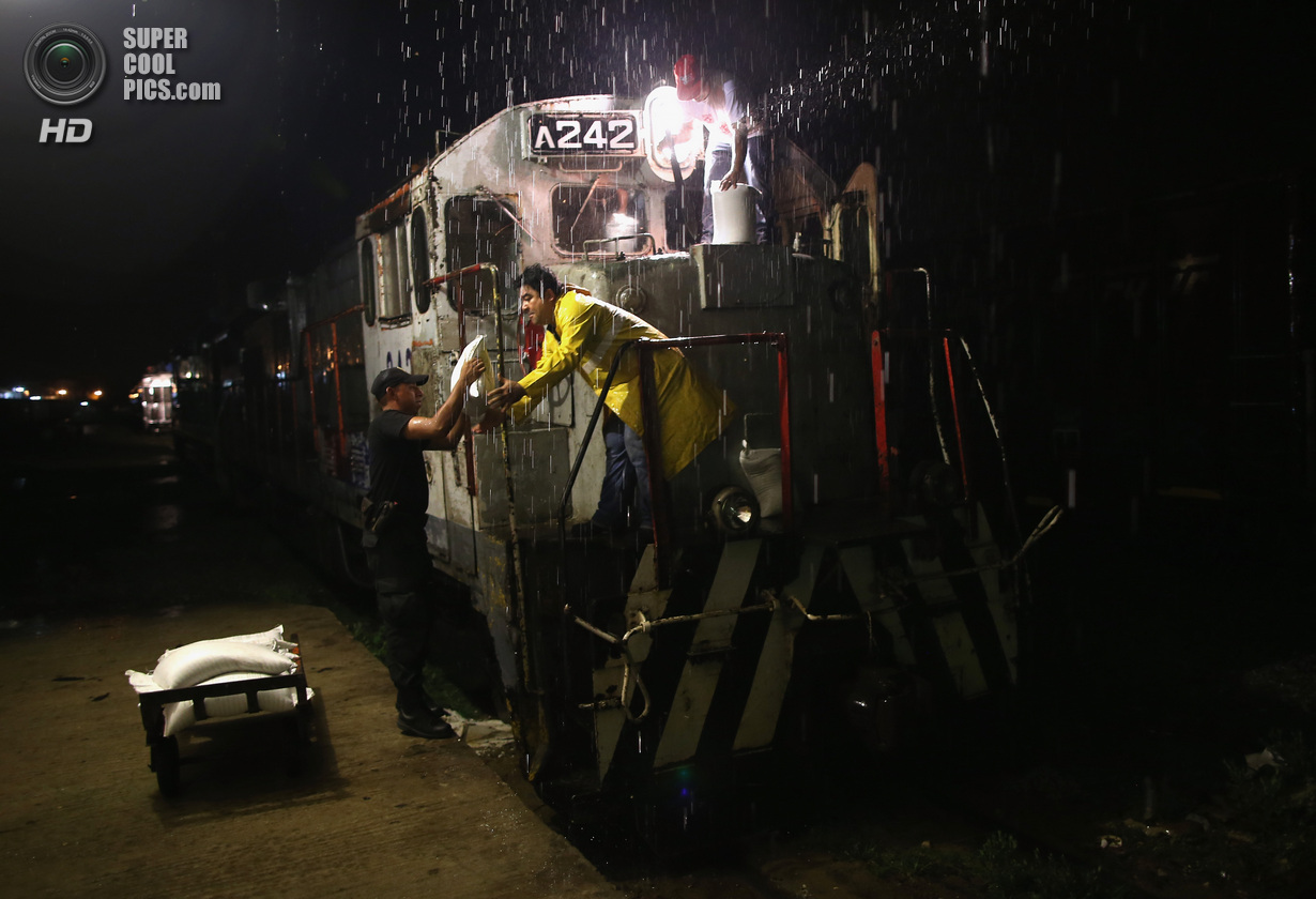 Мексика. Арриага, Чьяпас. 4 августа. Поездная бригада заправляет двигатель песком, чтобы разбрасывать его на скользкий от дождя рельсовый путь. (John Moore/Getty Images)