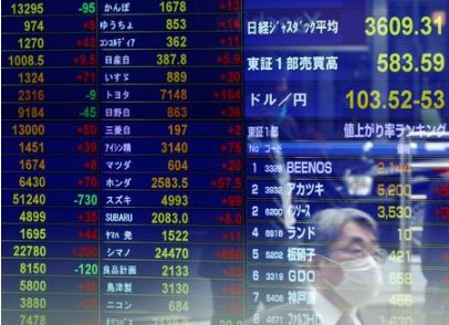 FILE PHOTO: A passersby wearing a protective face mask is reflected on screen displaying the Japanese yen exchange rate against the U.S. dollar and stock prices at a brokerage, amid the coronavirus disease (COVID-19) outbreak, in Tokyo, Japan November 6, 2020. REUTERS/Issei Kato/File Photo