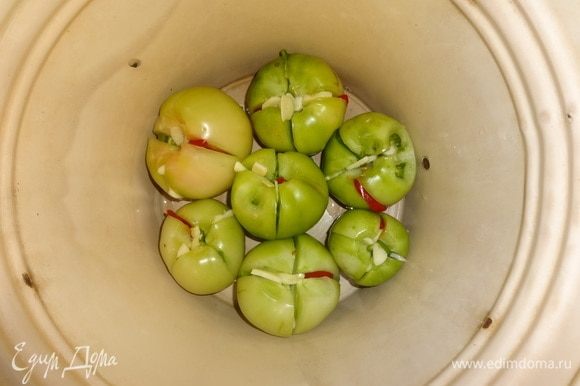 На дно эмалированного ведра или кастрюли уложить слой фаршированных помидоров.