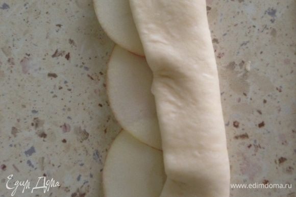 Разделить тесто на небольшие кусочки, каждый раскатать в пласт, нарезать на широкие полоски. Выложить яблоки на тесто так, чтобы края немного вылезали за тесто. Закрыть нижнюю часть яблок тестом.