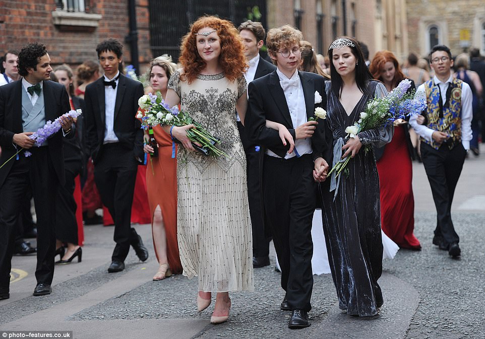 It all started so well: Cambridge revellers make their way to the ball holding bouquets of flowers on Monday evening