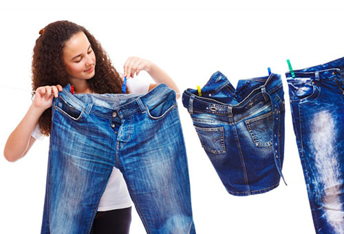 Девушка развешивает джинсы для сушки