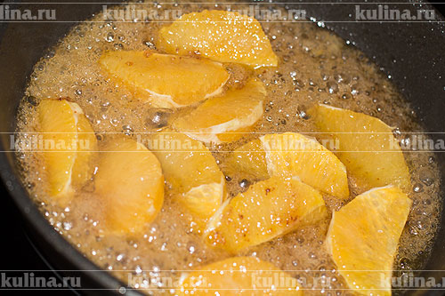 Апельсин очистить, нарезать, выложить в карамель и прогреть 1 минуту.