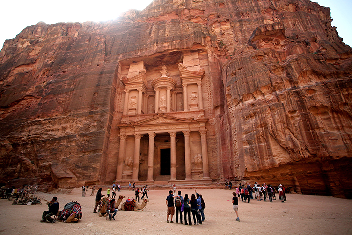 In this Thursday, March 6, 2014 photo, tourists stand in front of the rock-hewn Al Khazneh, Arabic for the Treasury, in the ancient city of Petra, Jordan. The kingdom’s launched an ecotourism project with the establishment of three camps in the Petra region, the first of 22 proposed eco-camps . The camps will eventually connect three areas in Jordan including the Dana Biosphere Reserve located in south-central Jordan. (AP Photo/Mohammad Hannon)