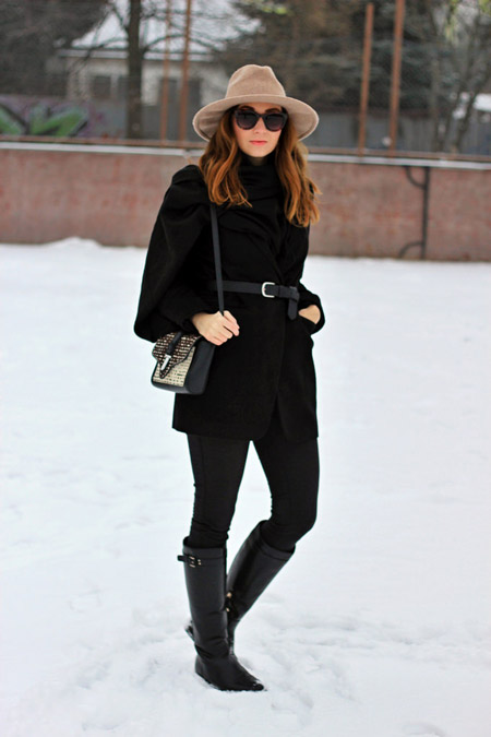 Девушка в черных сапогах и пальто с ремнем на талии, бежевая шляпа