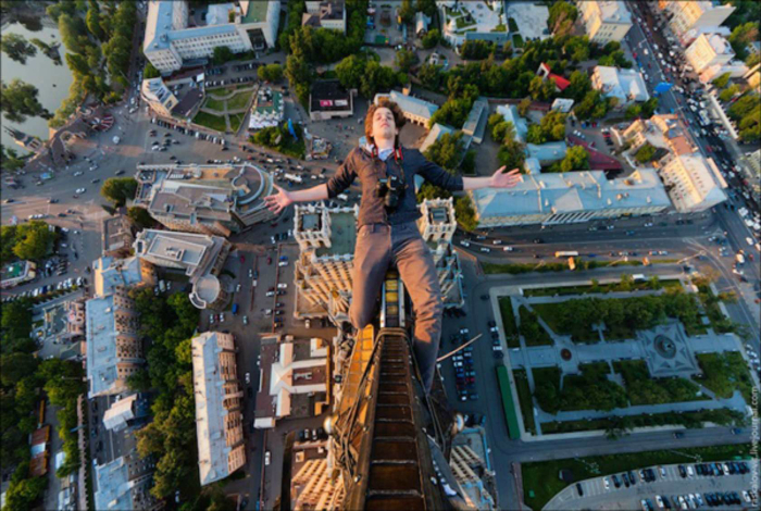 Бестрашный парень делает селфи вниз головой на огромной высоте.