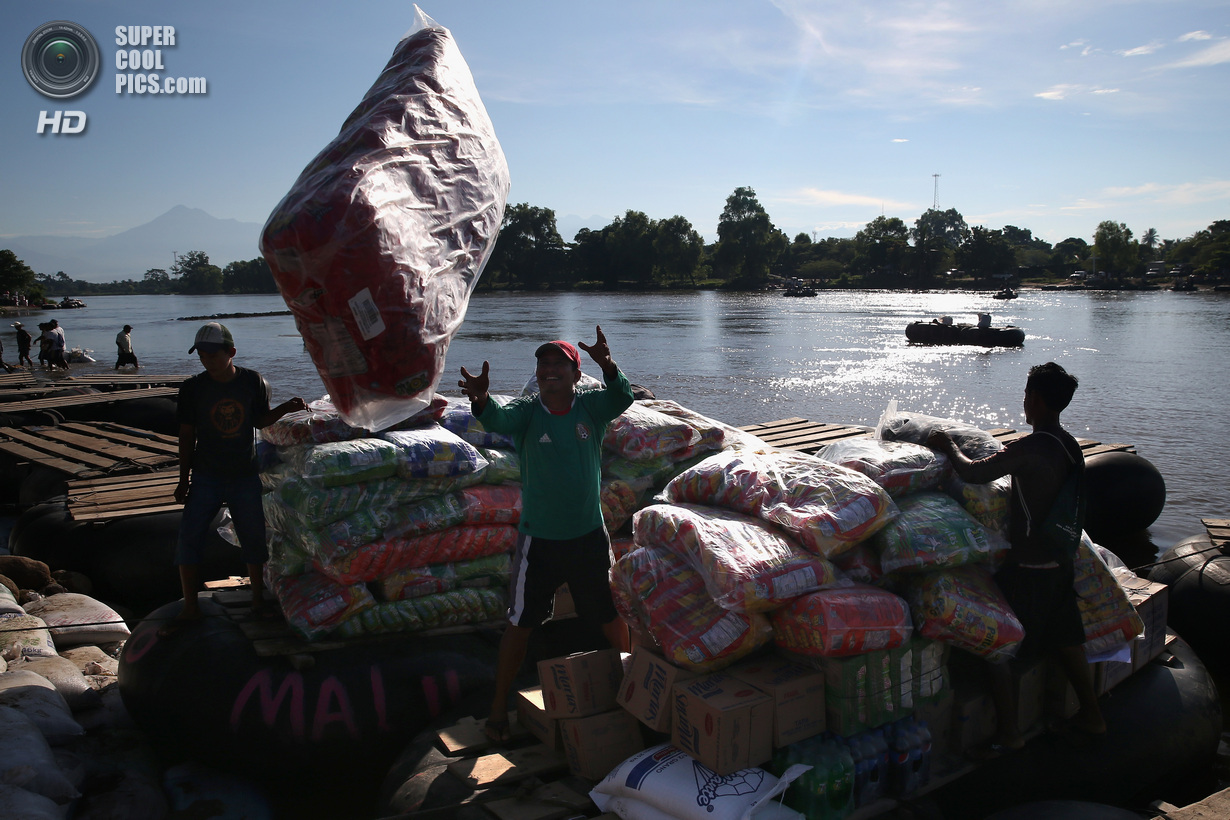 Мексика. Сьюдад-Идальго, Чьяпас. 2 августа. Гватемальские торговцы выгружают плот с товарами, нелегально провезёнными через границу. (John Moore/Getty Images)