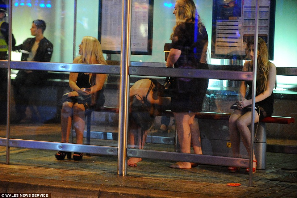 Waiting for the bus: Four women - two barefoot - take refuge in a bus shelter on New Year's Eve in Cardiff