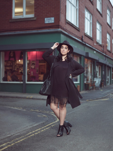 Девушка в черной шляпе, пальто и черное платье с бахромой на подоле