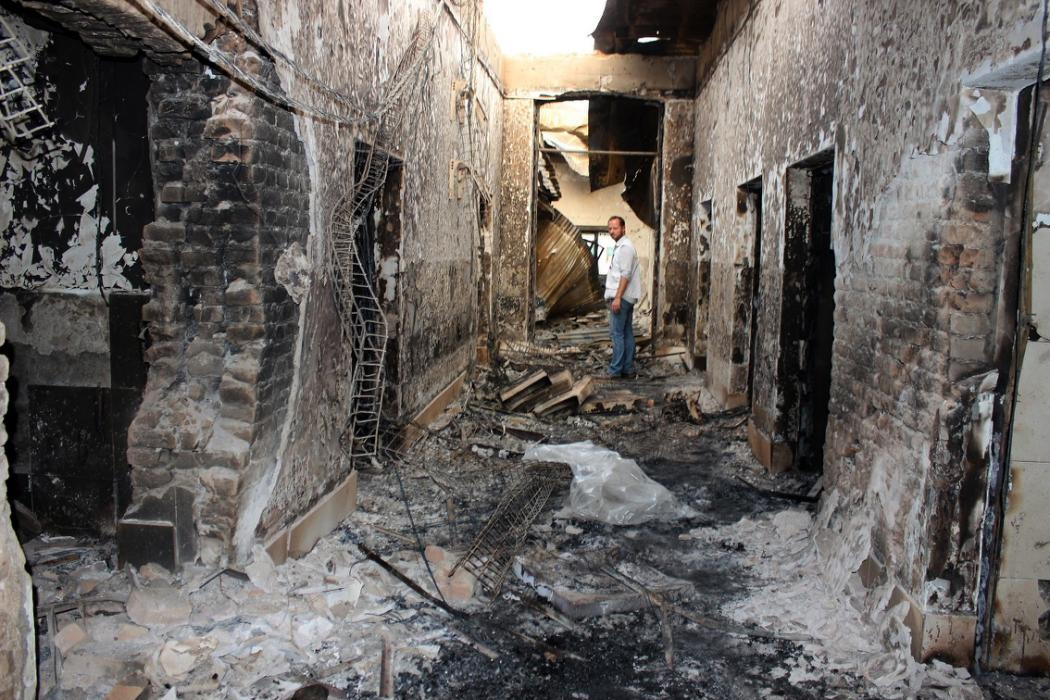In this Friday, Oct. 16, 2015 photo, an employee of Doctors Without Borders stands inside the charred remains of their hospital after it was hit by a U.S. airstrike in Kunduz, Afghanistan. Christopher Stokes, general director of Doctors Without Borders, which is also known by its French abbreviation MSF, whose hospital in northern Afghanistan was destroyed in a U.S. airstrike, says the extensive, quite precise destruction of the bombing raid casts doubt on American military assertions that it was a mistake. (Najim Rahim via AP)