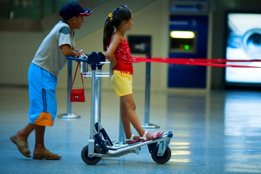Two children playing with a luggage cart in the airport. Rome Italy