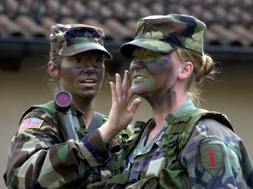 1st Infantry Division soldiers, Sgt. Jessica Lanuto and Sgt. Kenda Worthley, apply camouflage prior to embarking on the Headquarters Companys Big Red One Challenge at Leighton Barracks, Wuerzburg, Germany.  The BRO Challenge is an overnight training event where soldiers navigate from point to point and are tested on a number of skills considered essential knowledge for noncommissioned officers.  (Photo by Master Sgt. Larry Lane)