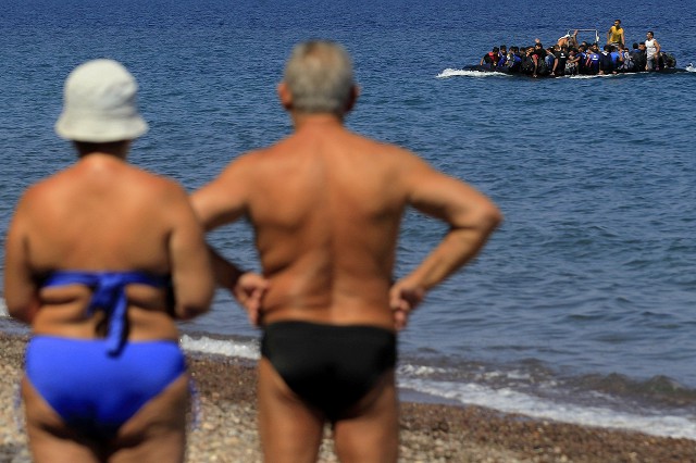 Отдыхающие на греческом острове Лесбос наблюдают за мигрантами из Сирии. Более 7 тысяч мигрантов прибыли на остров Лесбос за три…