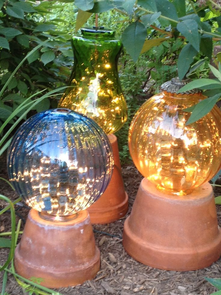 Garden lights made from flower pots and old lamp globes with strings of white lights in the globes.: 