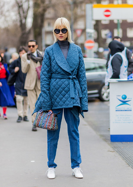 Модель в синих брюках, куртке и серая водолазка