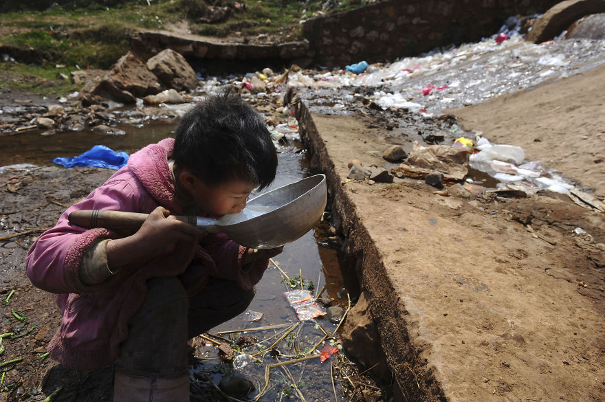 Ребенок пьет воду у ручья в Фуюань округа