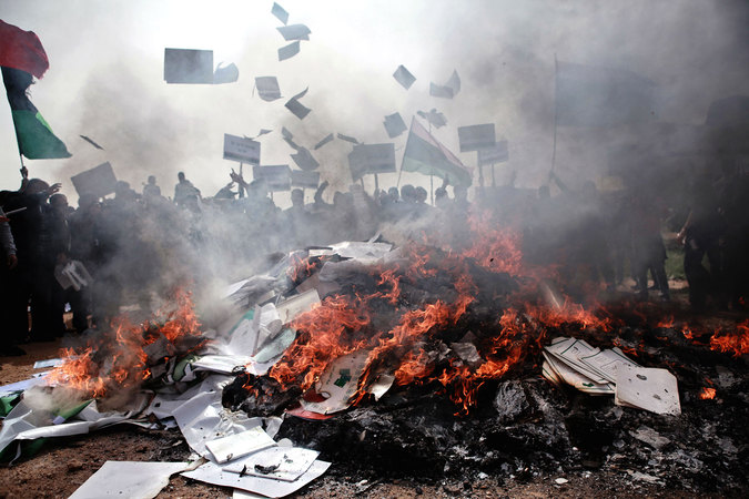 Жители Бенгази сжигают портреты Муамара Каддафи, плакаты с его цитатами и "Зеленую книгу" Каддафи во время гражданской войны.