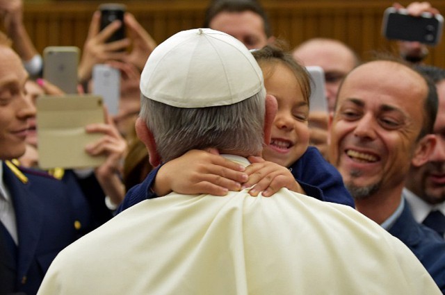 Девочка обнимает папу Римского Франциска во время встречи папы в Ватикане с членами семей итальянских полицейских, погибших при исполнении служебных…