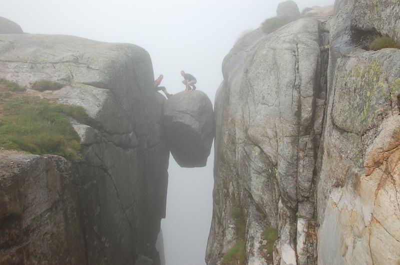 Люди фотографируются на висячем камне Кьёрагболтен, зажатом между двух скал