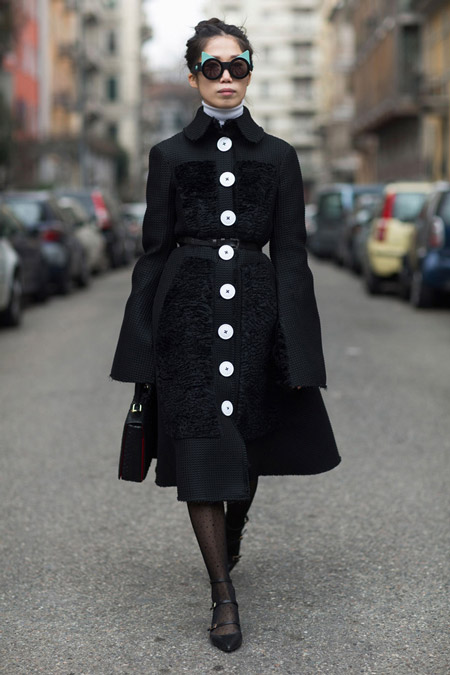 Модель в черном классическом пальто в белыми пуговицами