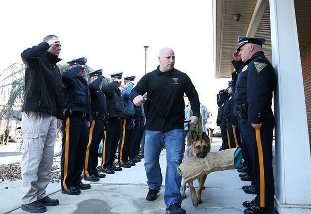 8. Офицеры прощаются с неизлечимой собакой из отряда K9, которую ведут к ветеринару на усыпление люди, фото