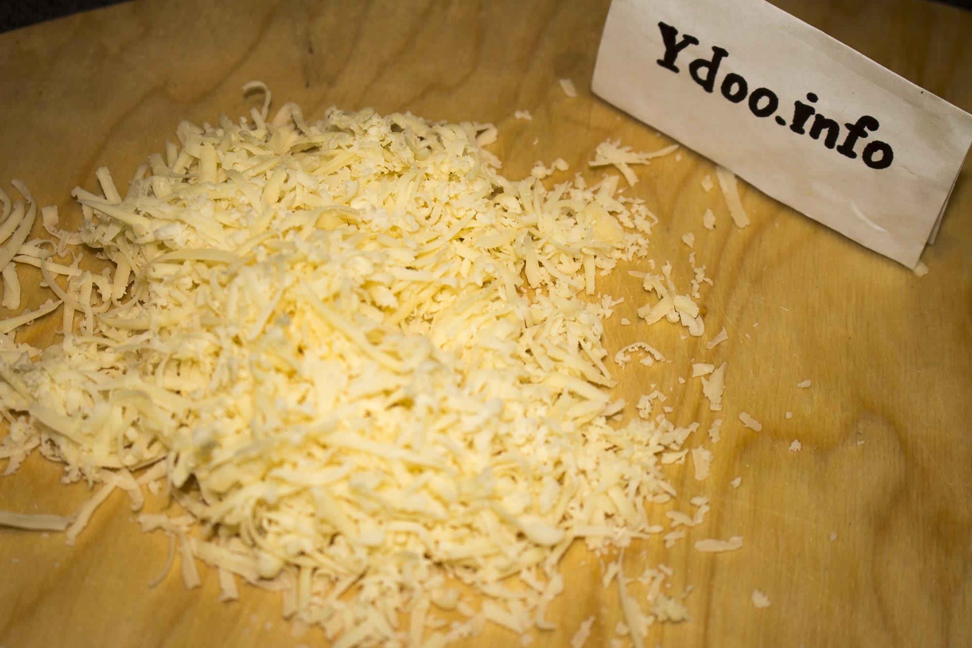 тертый твердый сыр на деревянной разделочной доске