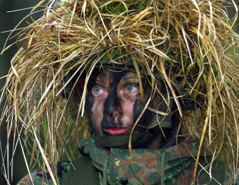 Private Dajana Bartczewski wears a full camouflage helmet and camouflage paint on her face during German army manuevers near Augustdorf, western Germany, 125 miles northeast of Duesseldorf, Tuesday, Jan. 9, 2001. It was the first time that female soldiers joined a military exercise in combat units and were permitted to handle weapons. The women joined the combat unit for the first time last Tuesday. (AP Photo/Frank Augstein)