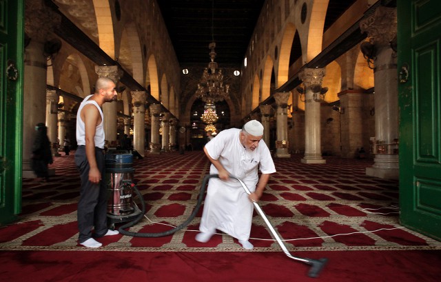 Палестинец убирается в мечети Аль-Акса в Старом городе Иерусалима после столкновений палестинцев с израильским ОМОНом
