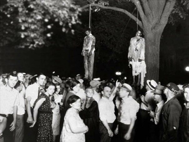 Этот кадр был сделан в 1930, когда толпа из 10 тысяч белых повесила двух чернокожих мужчин за изнасилование белой женщины и убийство её молодого человека. Толпа «освободила» преступников из тюрьмы, чтобы линчевать. Поразительный контраст – радостные лица людей как фон для растерзанных трупов.