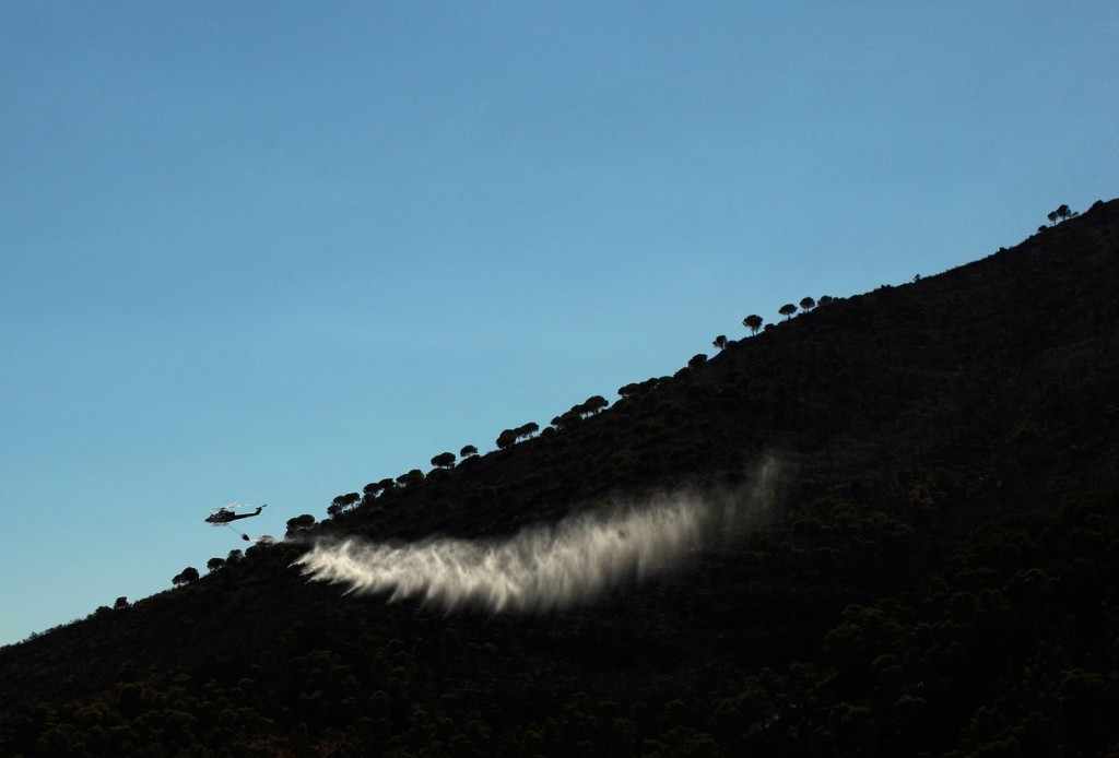 Вертолет тушит пожар неподалеку от города Михас. Фото: Reuters