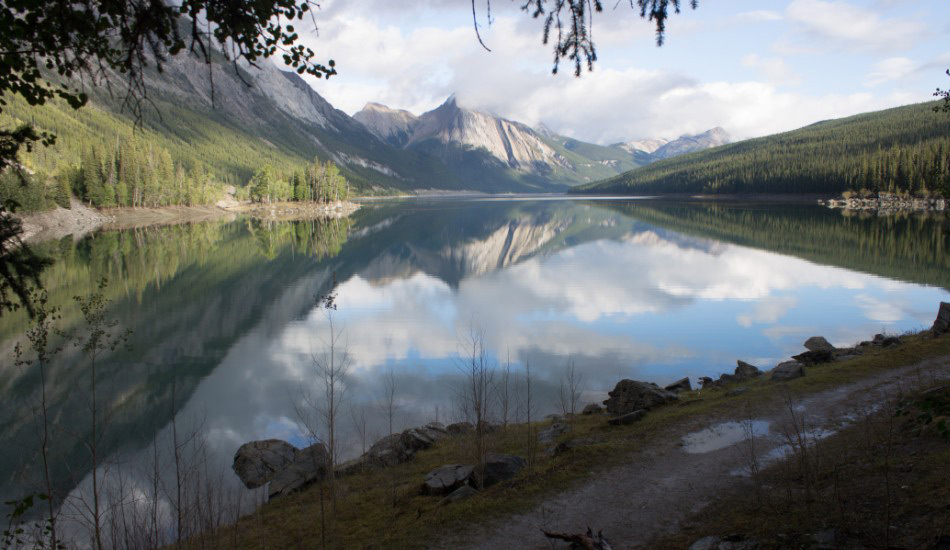 Озеро Медисин, Канада
Национальный парк в канадской провинции Альберта выходит к озеру, настолько таинственному, что, скорее всего, вы его не обнаружите, ведь каждую зиму вода в нем попросту исчезает. Но дело вовсе не в испарении. Озеро Медисин скорее напоминает гигантскую ванну длиной 6 километров и глубиной 30 метров, которая наполняется летом, когда таящие в горах ледники попадают в реку Малинье. У реки есть несколько своеобразных воронок — в озере Медисин находится как раз одна из них, — которые отводят потоки реки в систему подземных пещер, и затем река вновь выходит на поверхность в каньоне Малинье. Несмотря на огромные объемы воды с ледников, весь процесс поглощения занимает всего несколько недель. Тайна озера Медисин была разгадана только в 1970-х годах.