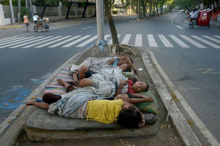 Бездомные дети спят на выброшенном матрасе посреди дороги.