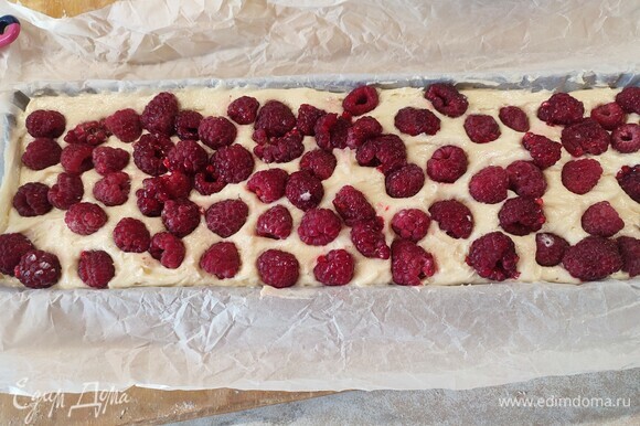 Выложить тесто в форму для выпечки, сверху выложить ягоды малины, слегка утопить в тесте. Выпекать 35 минут при температуре 180°C.